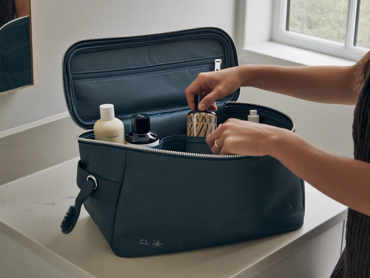 Grande trousse de toilette bleu canard ouverte sur un plan clair, compartiments et doublure visibles