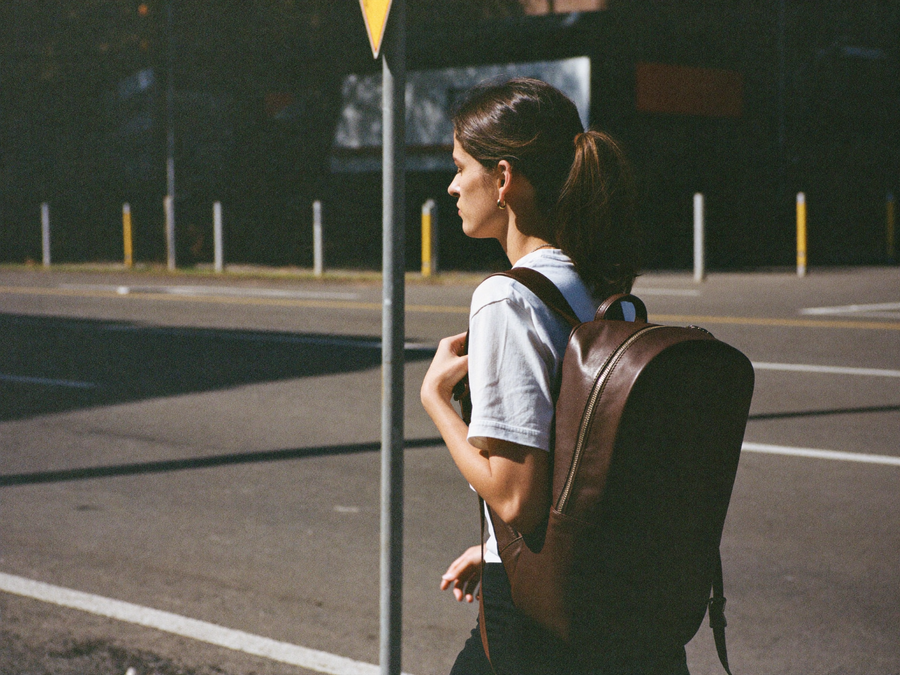 Femme portant un sac a dos en cuir dans une rue ensoleillee